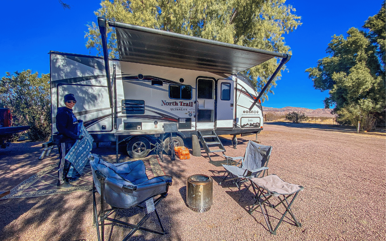 RV set up with chairs and fire pit outside.