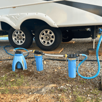 3 water filters hooked up from the spigot to an RV connected by hoses.
